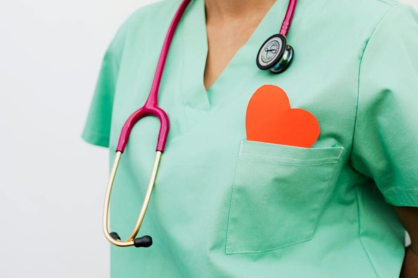 Person in scrubs with stethoscope and paper love heart