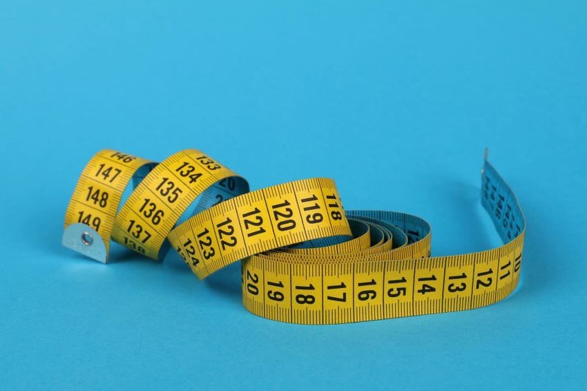 Measuring tape curling on a blue background